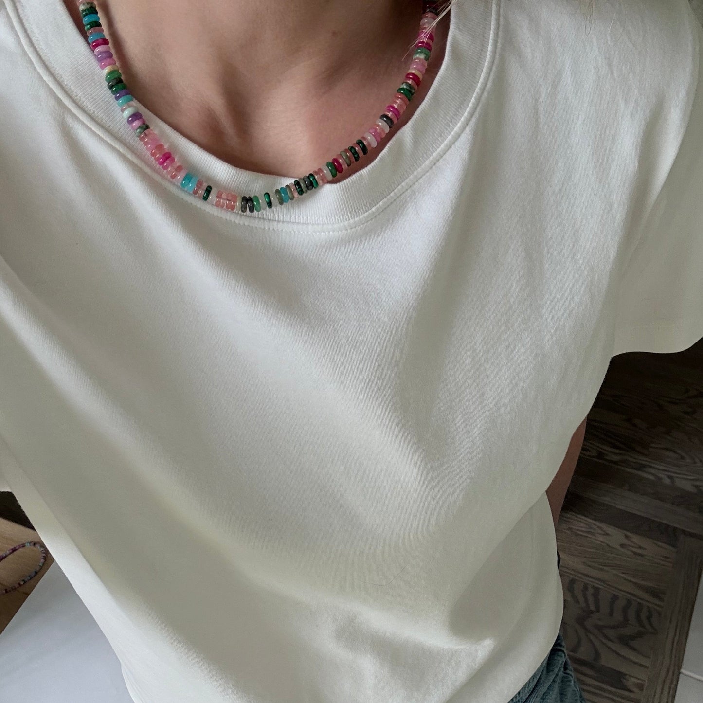 Close-up of a white garment with colorful trim on a wooden surface.