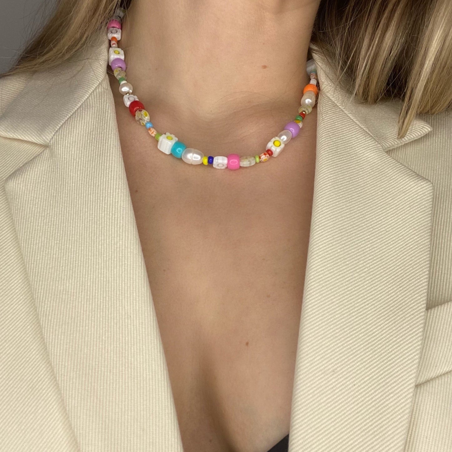 Colorful beaded necklace worn by a person in a beige blazer.