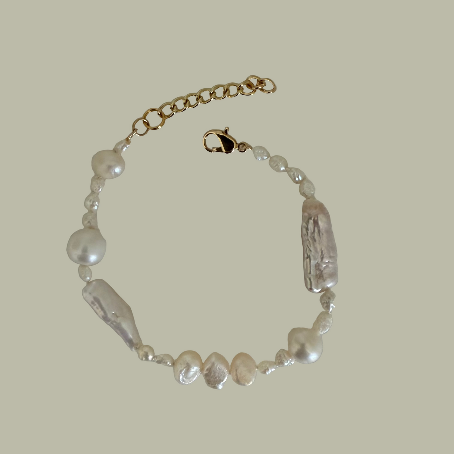 A bracelet with a combination of baroque freshwater pearls and gold filled closure, displayed on a flat surface.