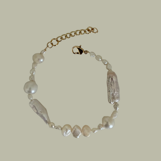 A bracelet with a combination of baroque freshwater pearls and gold filled closure, displayed on a flat surface.