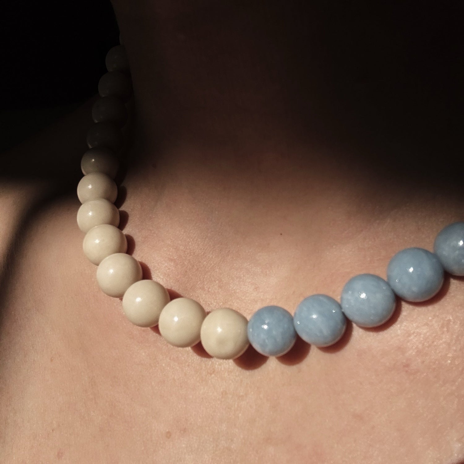 Necklace with round beads on a person's neck against a dark background