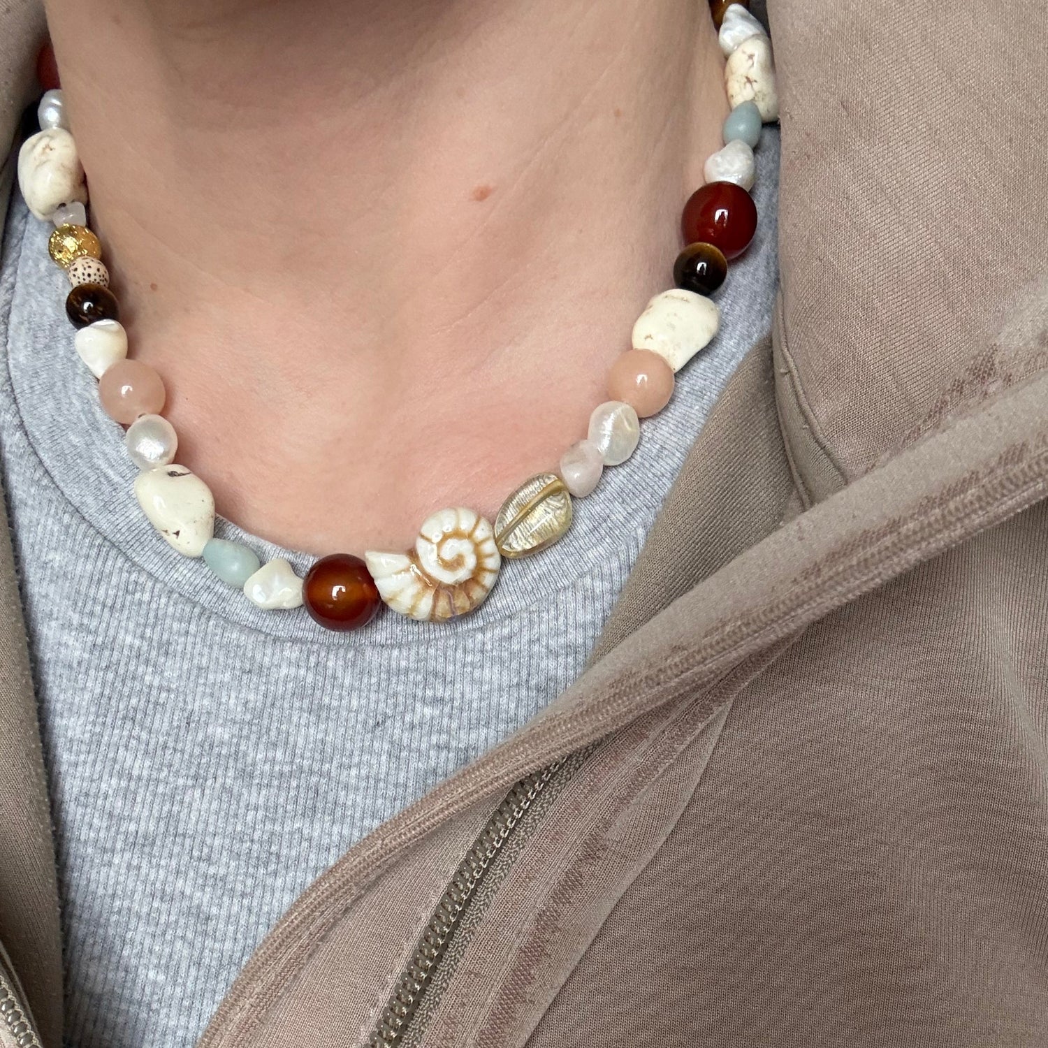Close-up of a person wearing a beaded necklace with a neutral background