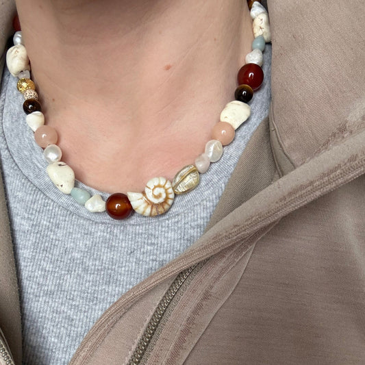 Close-up of a person wearing a beaded necklace with a neutral background