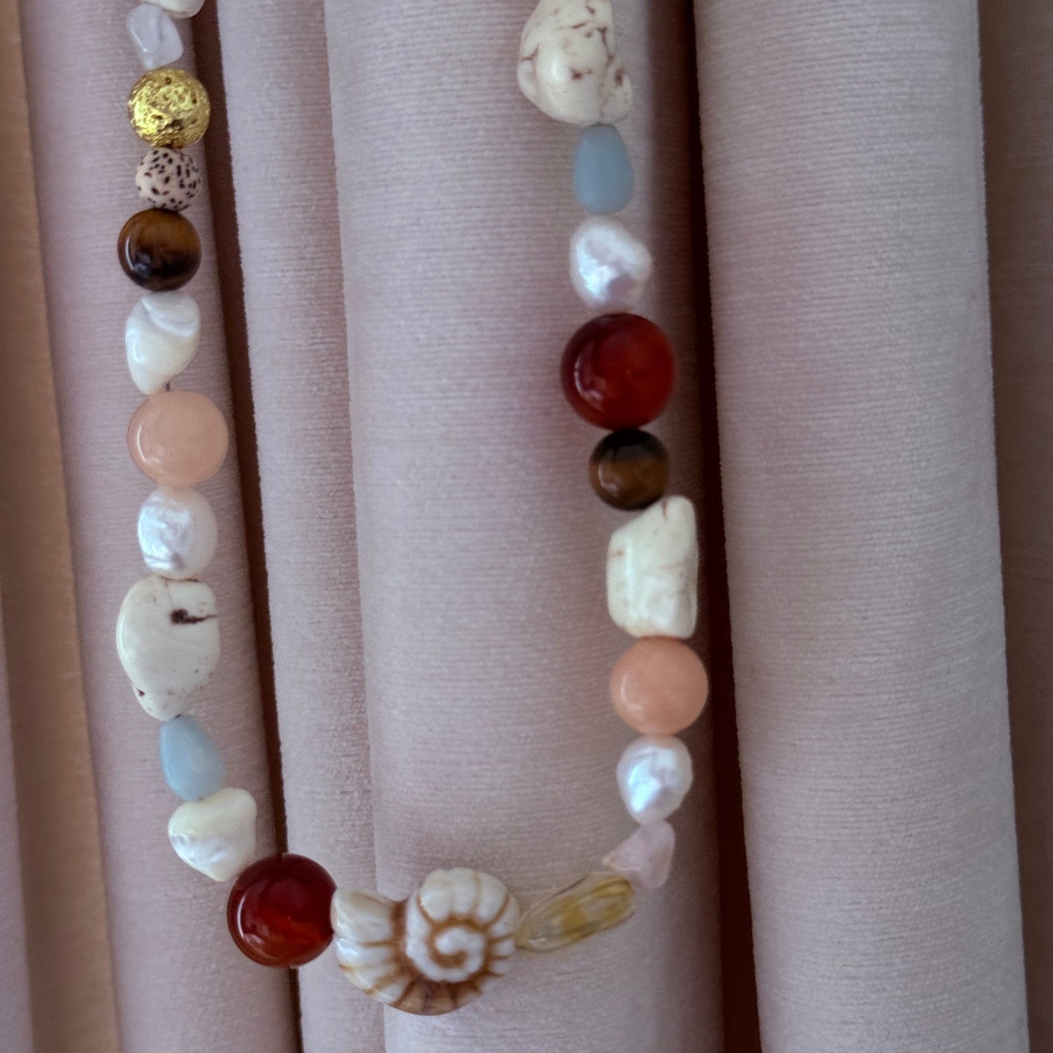 Necklace with multicolored beads on a beige fabric background