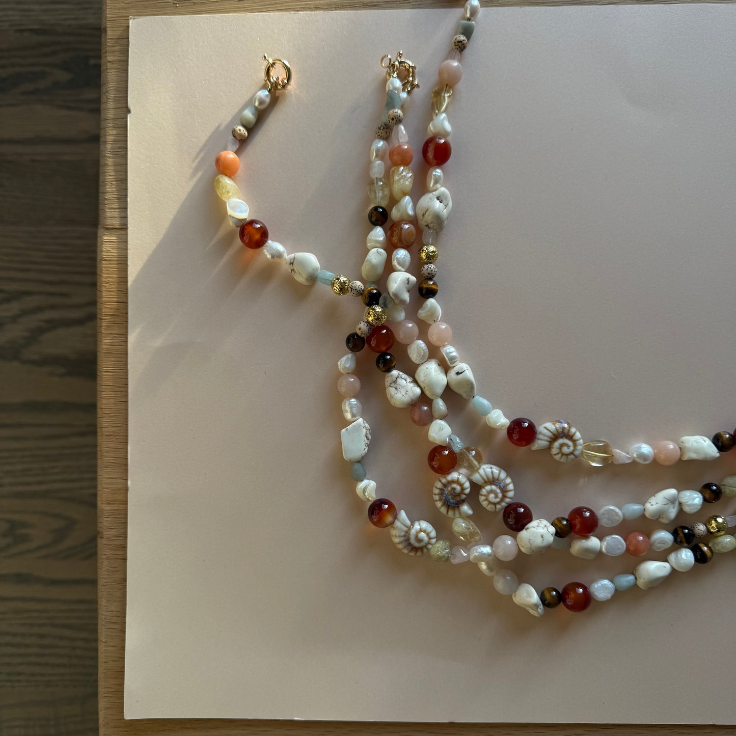 Beaded necklace on a light-colored card with a wooden surface background