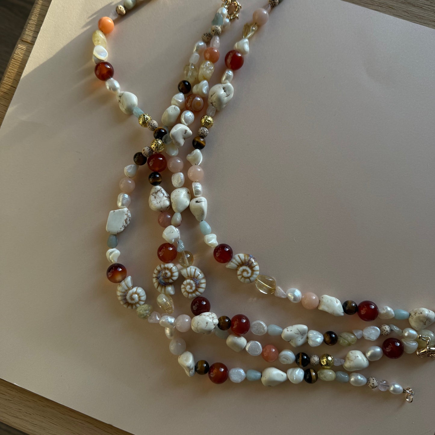Multistrand pearl necklace with red and gold accents on a light surface