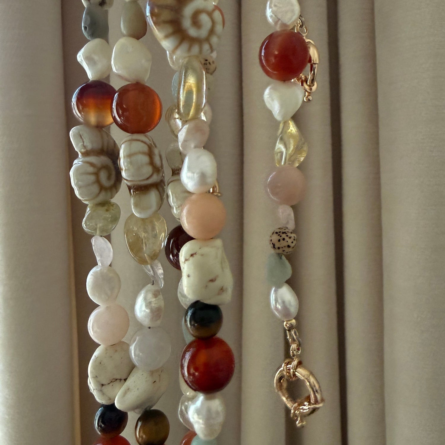Pearl necklaces with various colored beads on a neutral background