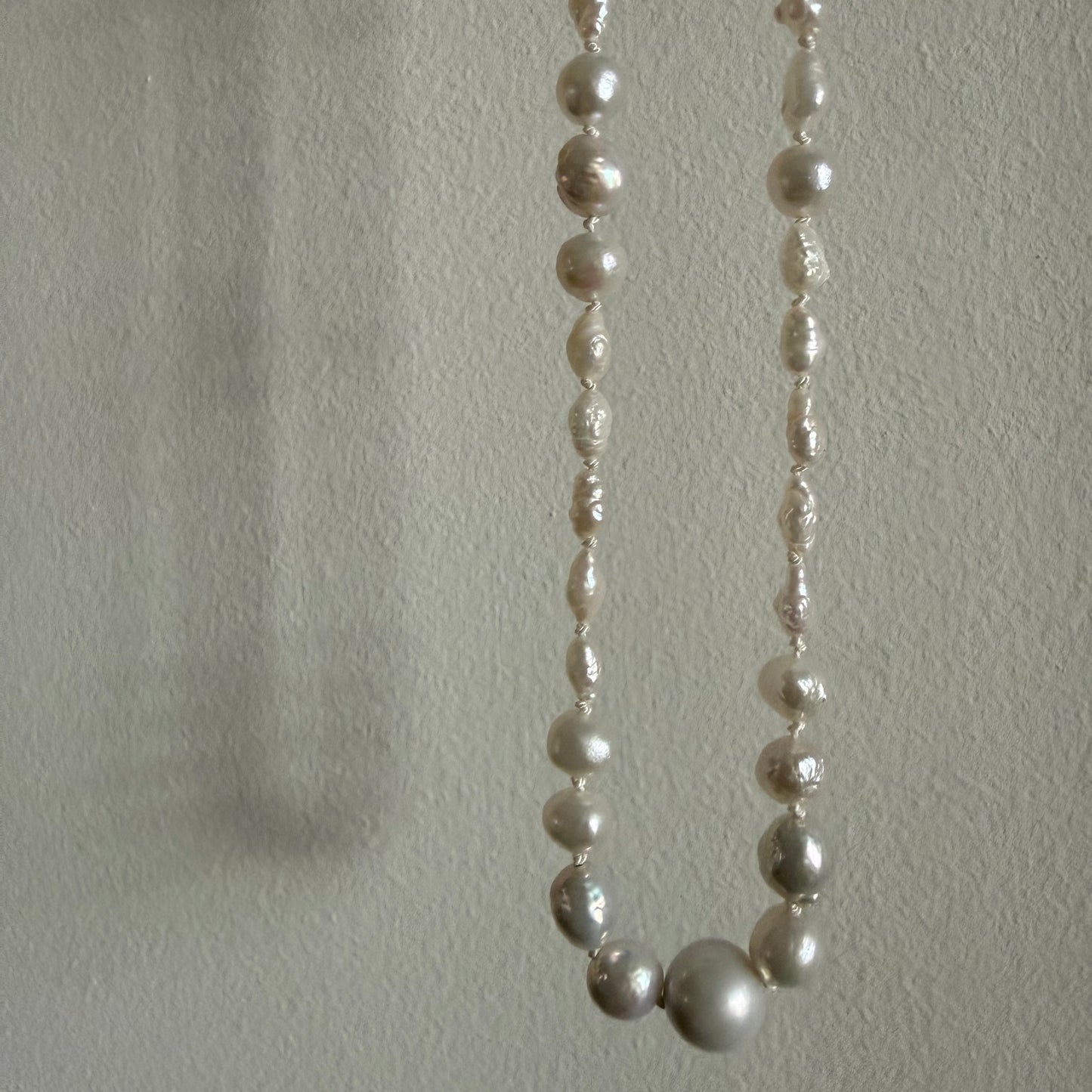 Pearl necklace on a textured light gray background