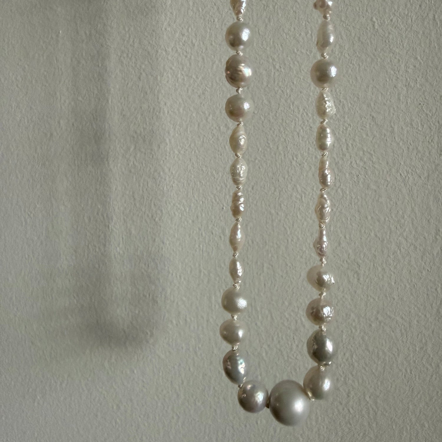 Pearl necklace on a textured light gray background