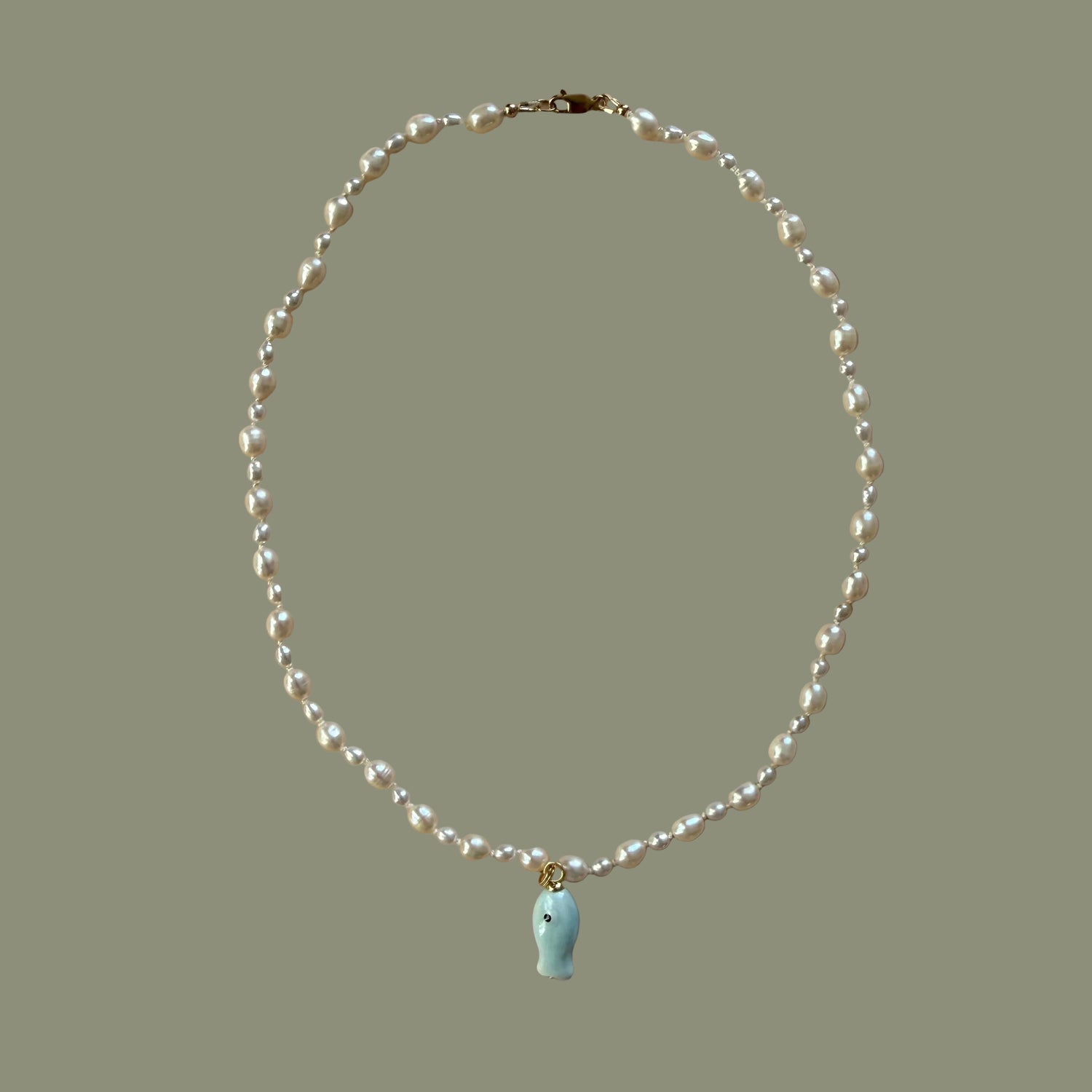 Pearl necklace with a small charm on a beige background