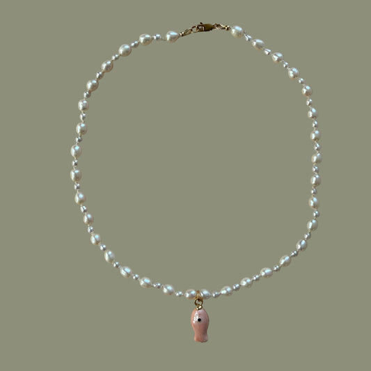Pearl necklace with a pink pendant on a beige background