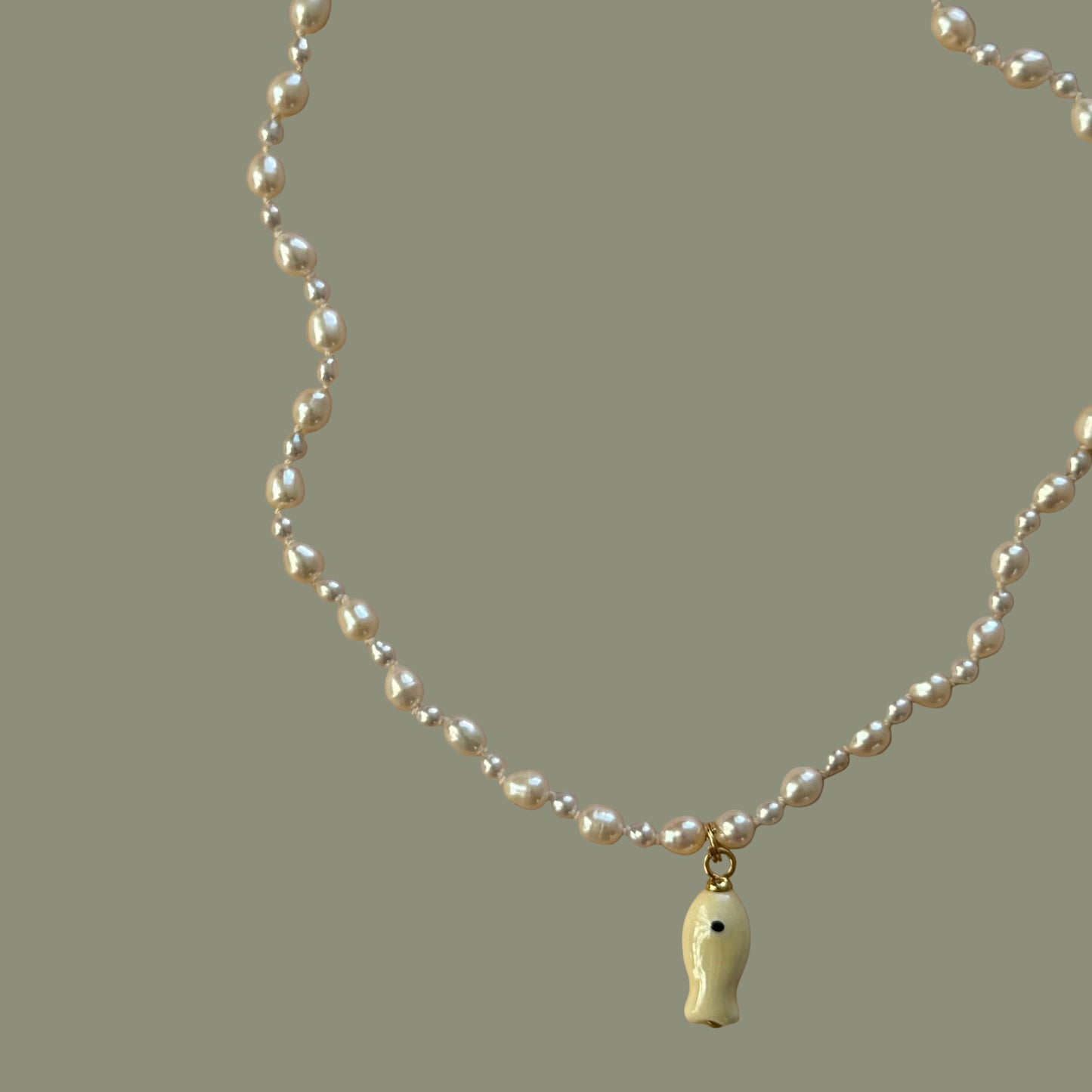 Pearl necklace with a gold clasp on a beige background