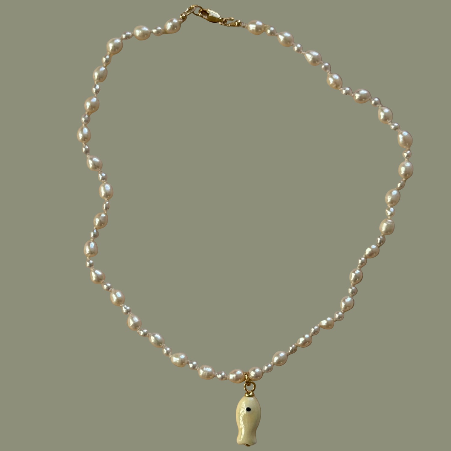 Pearl necklace with a gold clasp on a beige background
