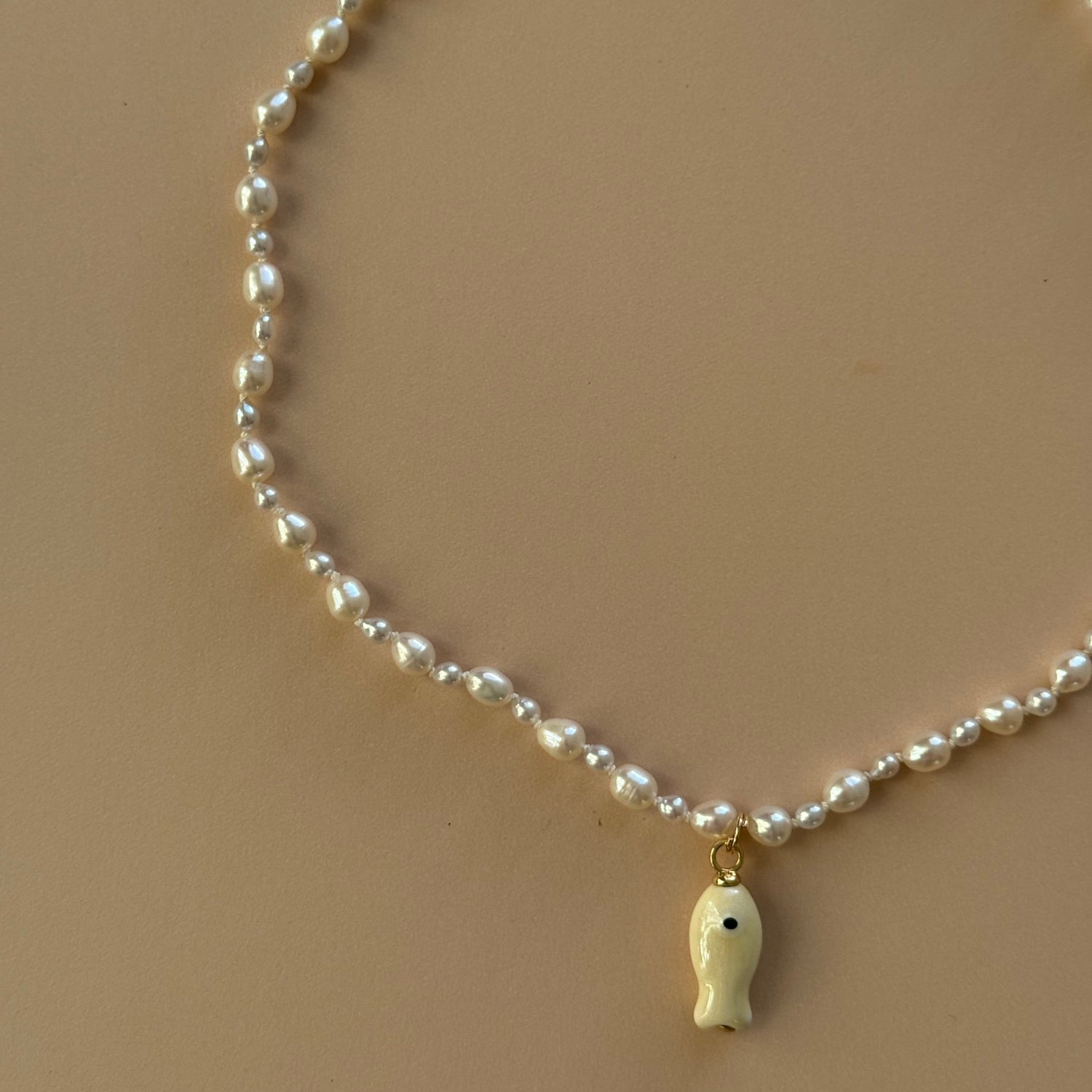 Pearl necklace with a gold clasp on a beige background