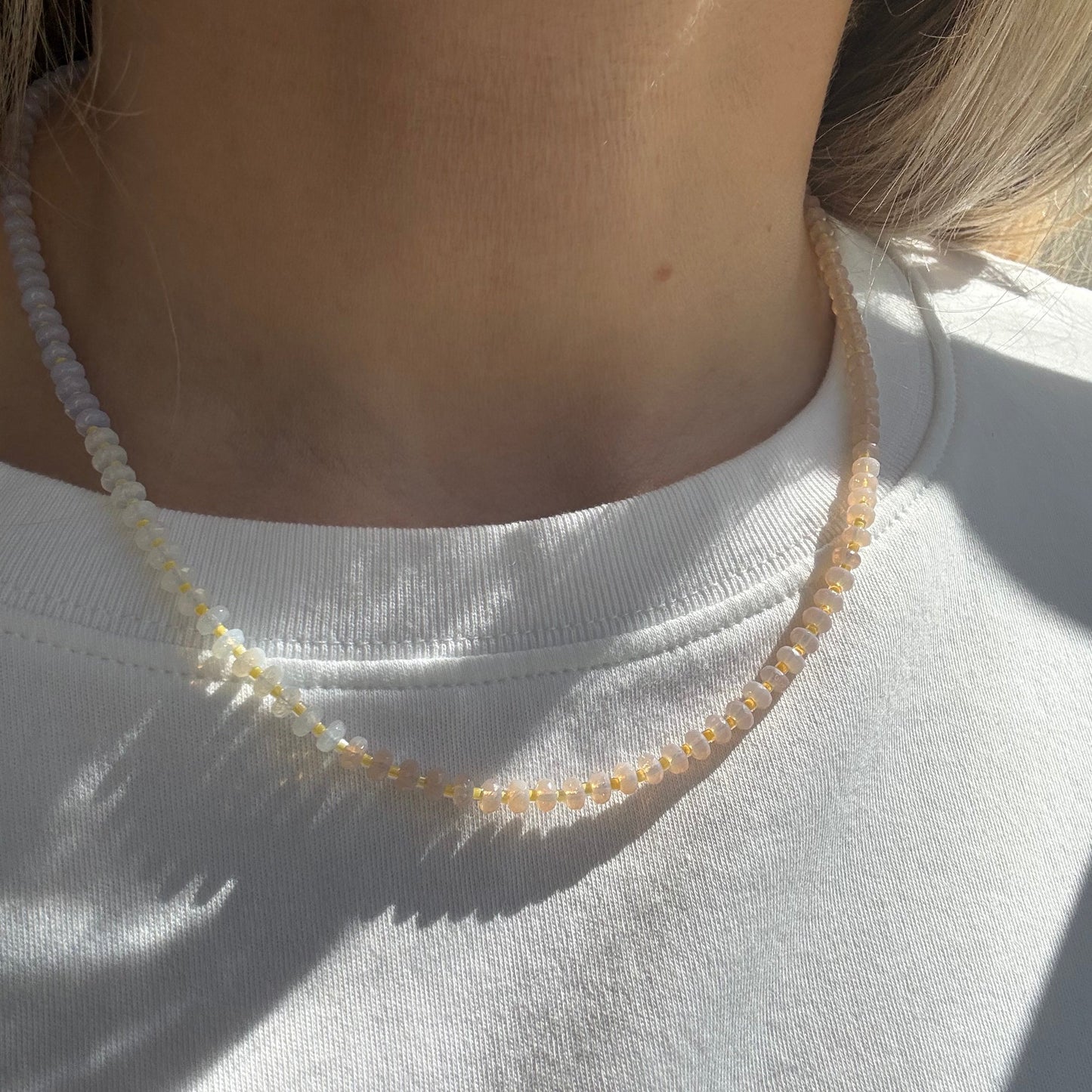 Close-up of a person wearing a white sleeveless top with a decorative trim.