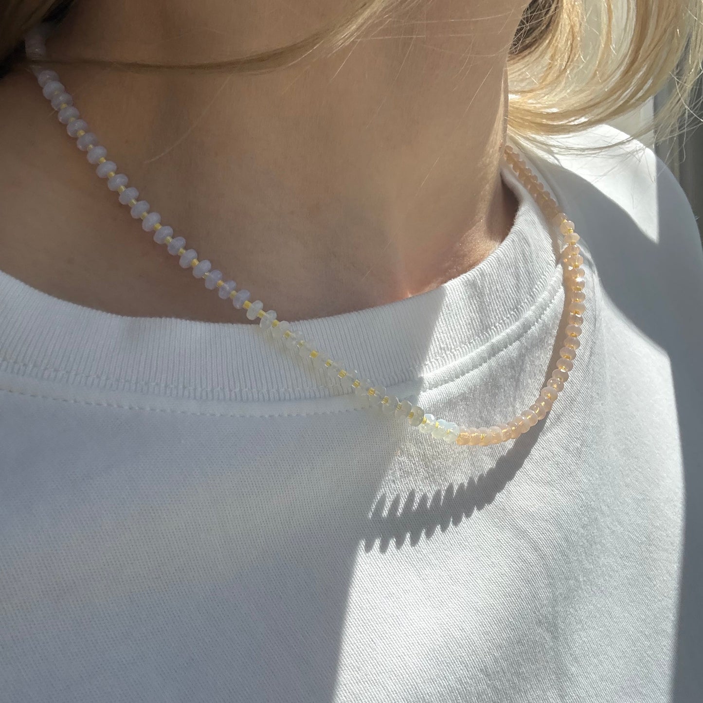 Close-up of a woman wearing a white wedding dress with a sheer overlay and thin straps.