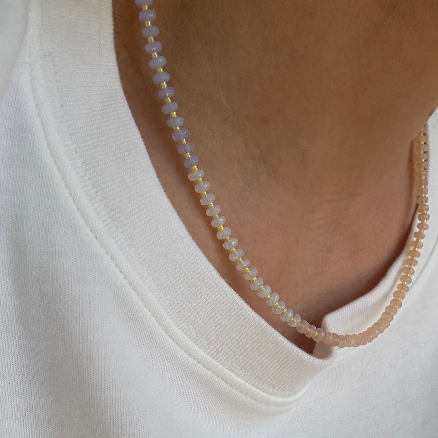 Close-up of a delicate beaded necklace on a white shirt
