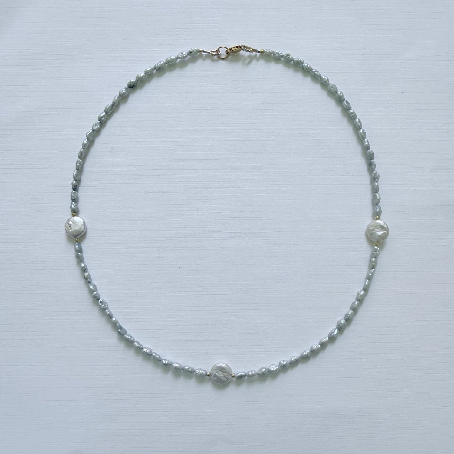 Necklace with small pearls on a light gray background