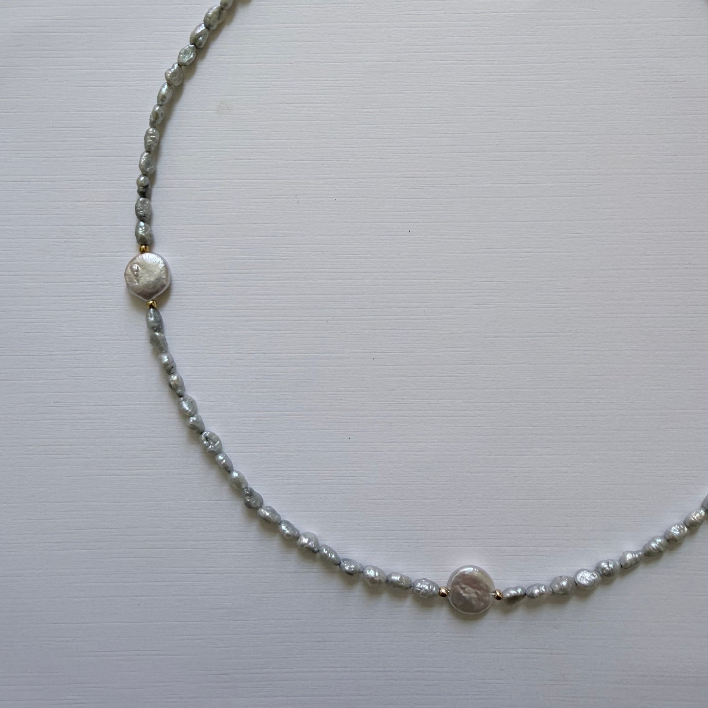 Necklace with small round freshwater coin pearls on a light gray background