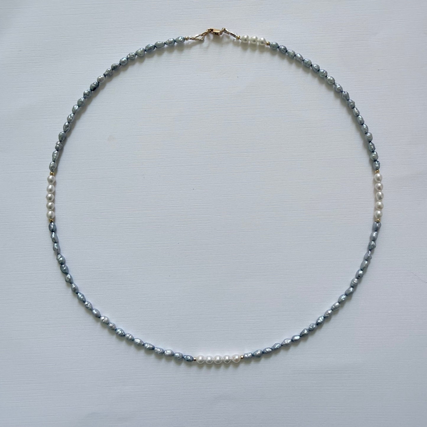 Necklace with small blue grey pearls on a light gray background