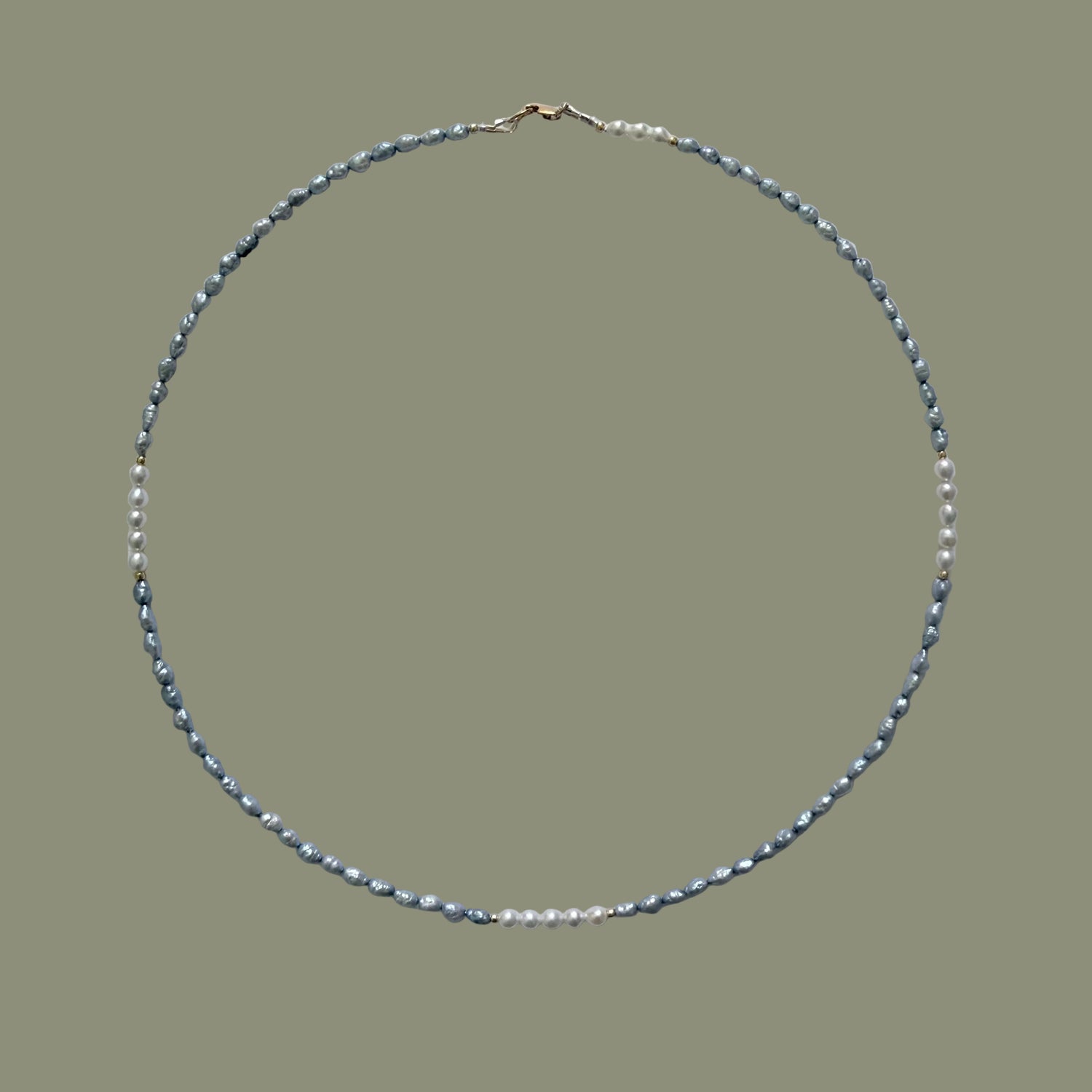 Necklace with blue grey and white pearls on a light gray background