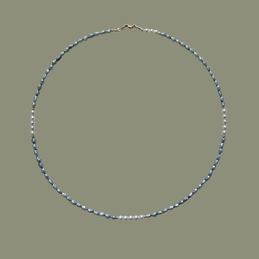 Necklace with blue grey and white pearls on a light gray background