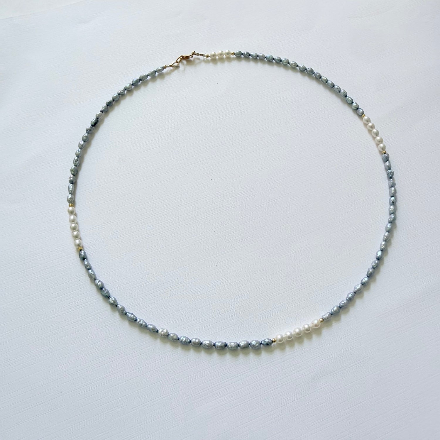 Necklace with blue and white pearls on a white surface