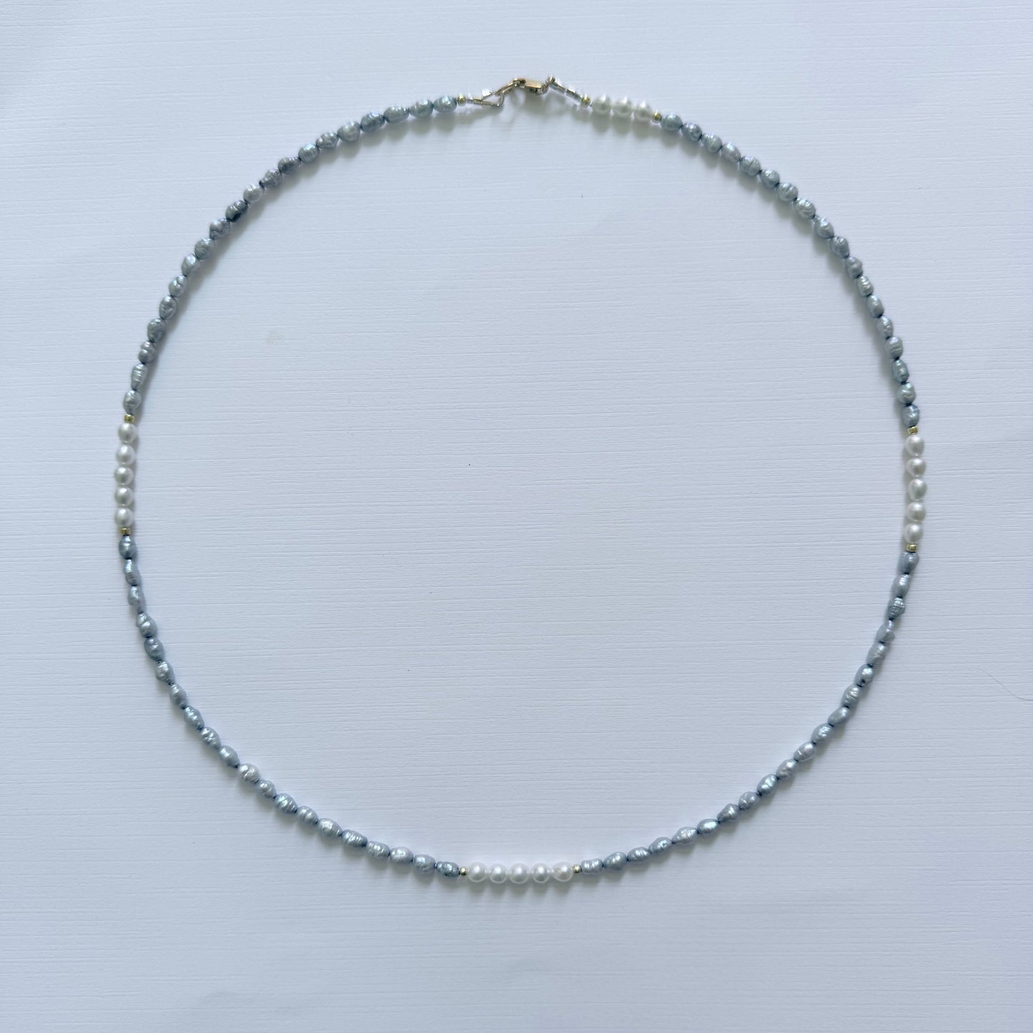 Necklace with small blue grey pearls on a light gray background