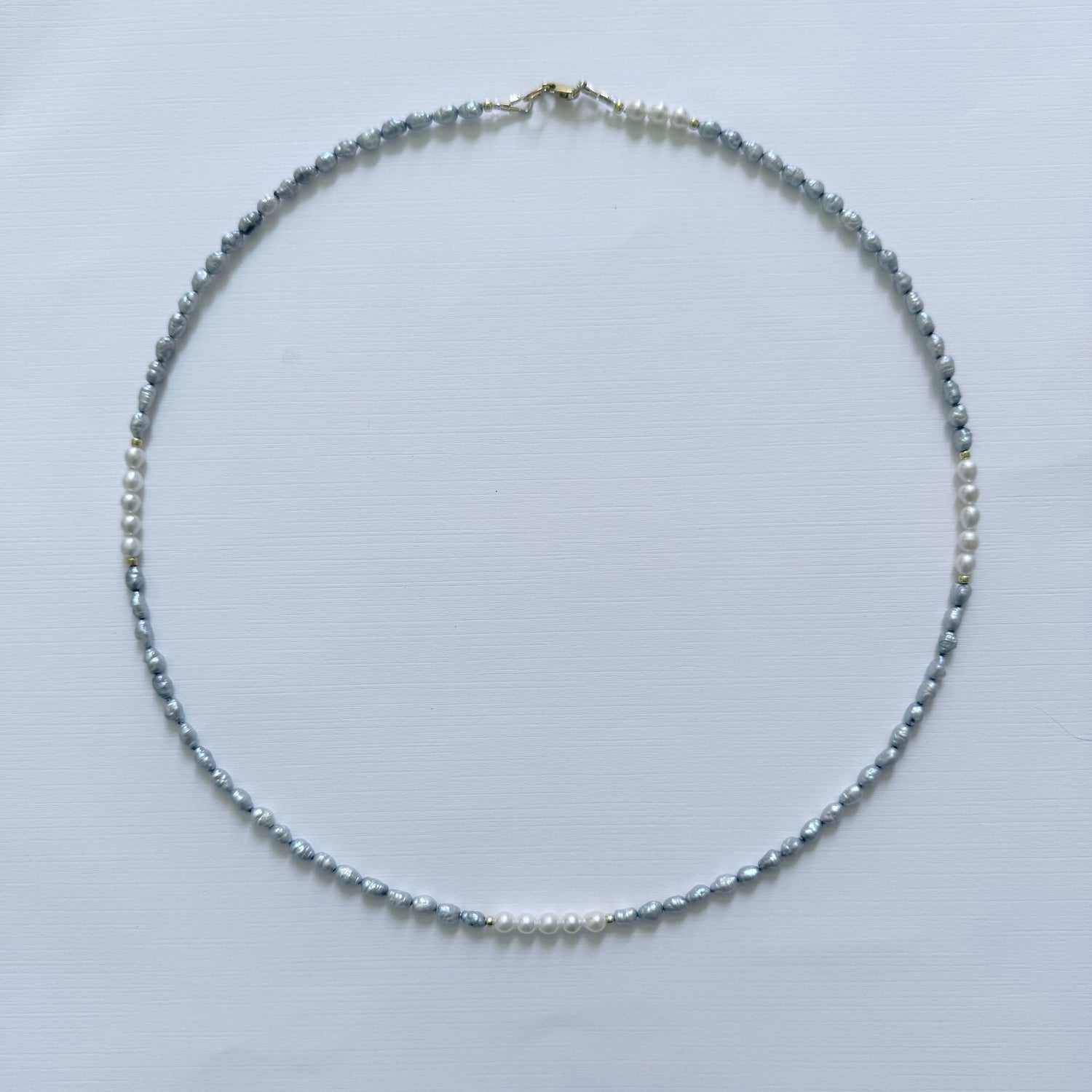 Necklace with small blue grey pearls on a light gray background