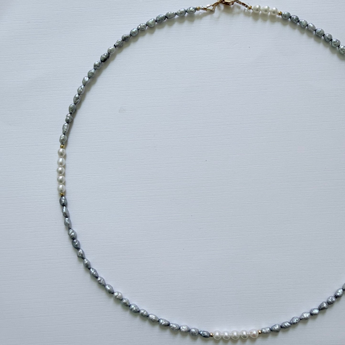 Necklace with small blue grey pearls on a light gray background