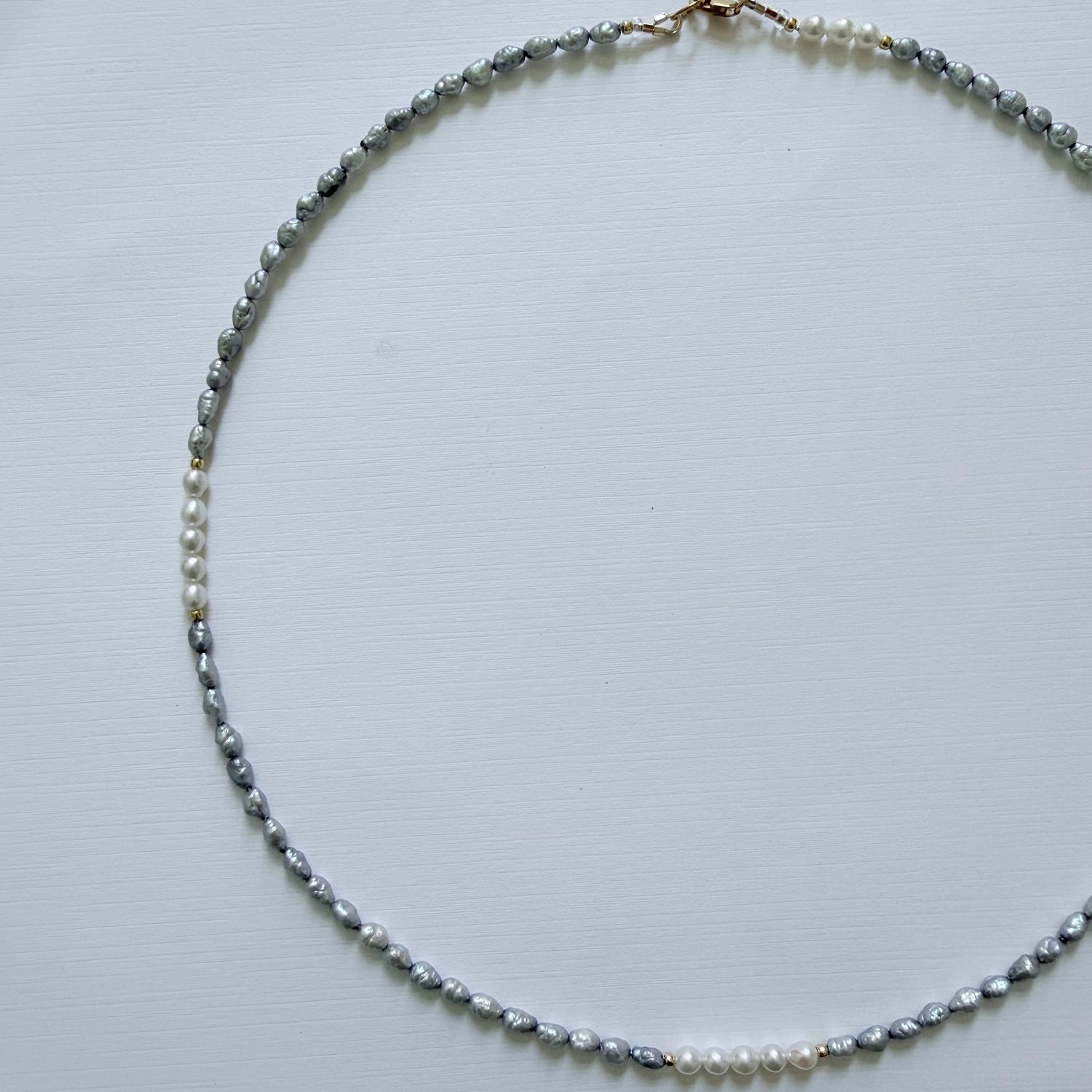 Necklace with small blue grey pearls on a light gray background