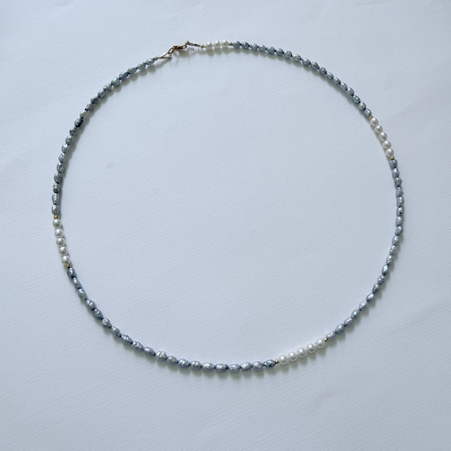 Necklace with small pearls on a light gray background
