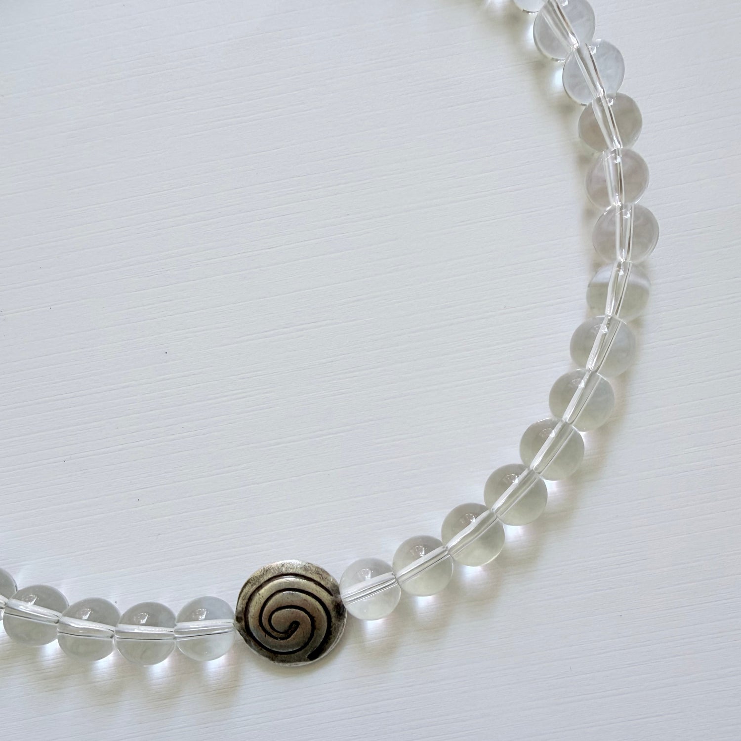 Clear beaded bracelet with a spiral charm on a white background