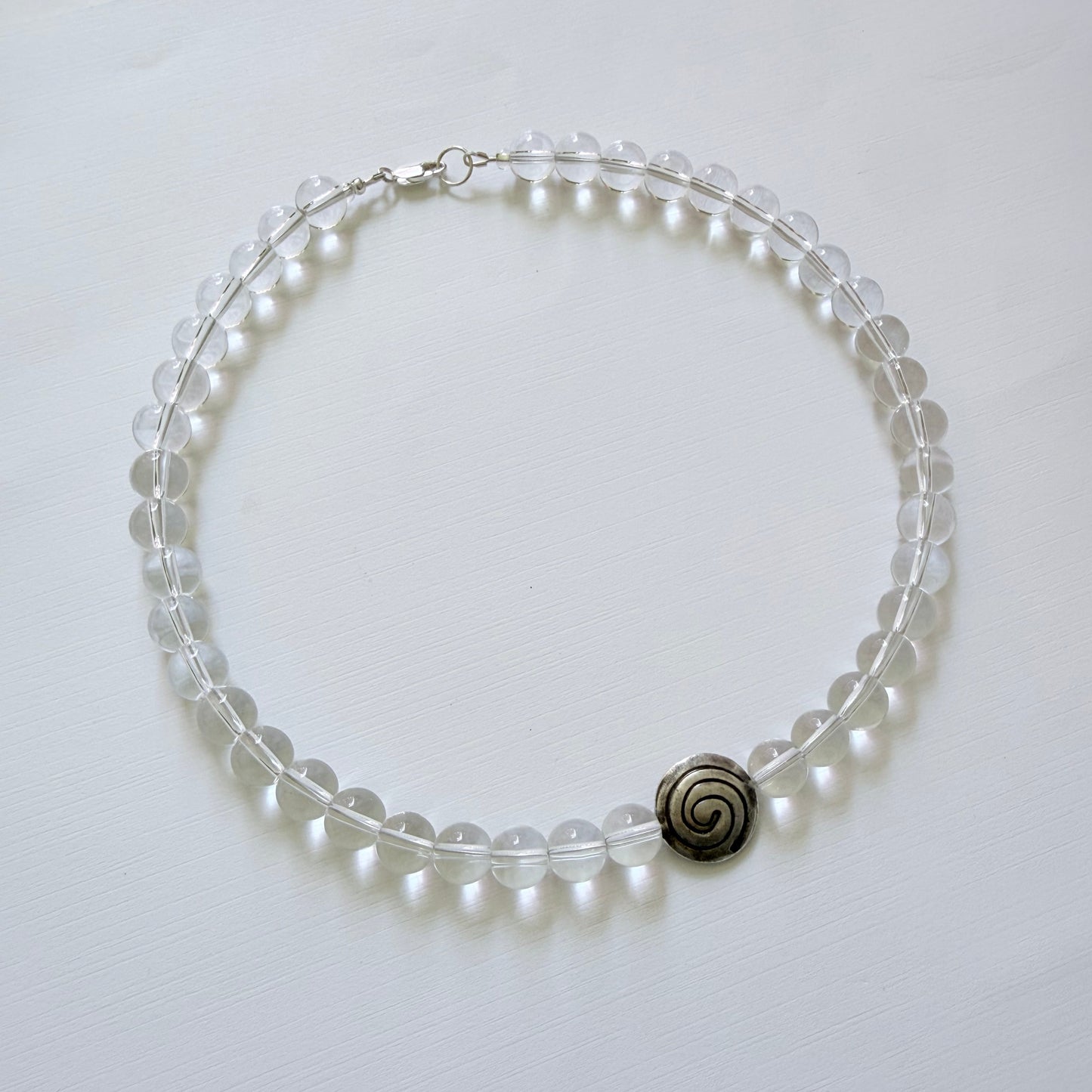 Pearl bracelet with a silver spiral charm on a white background