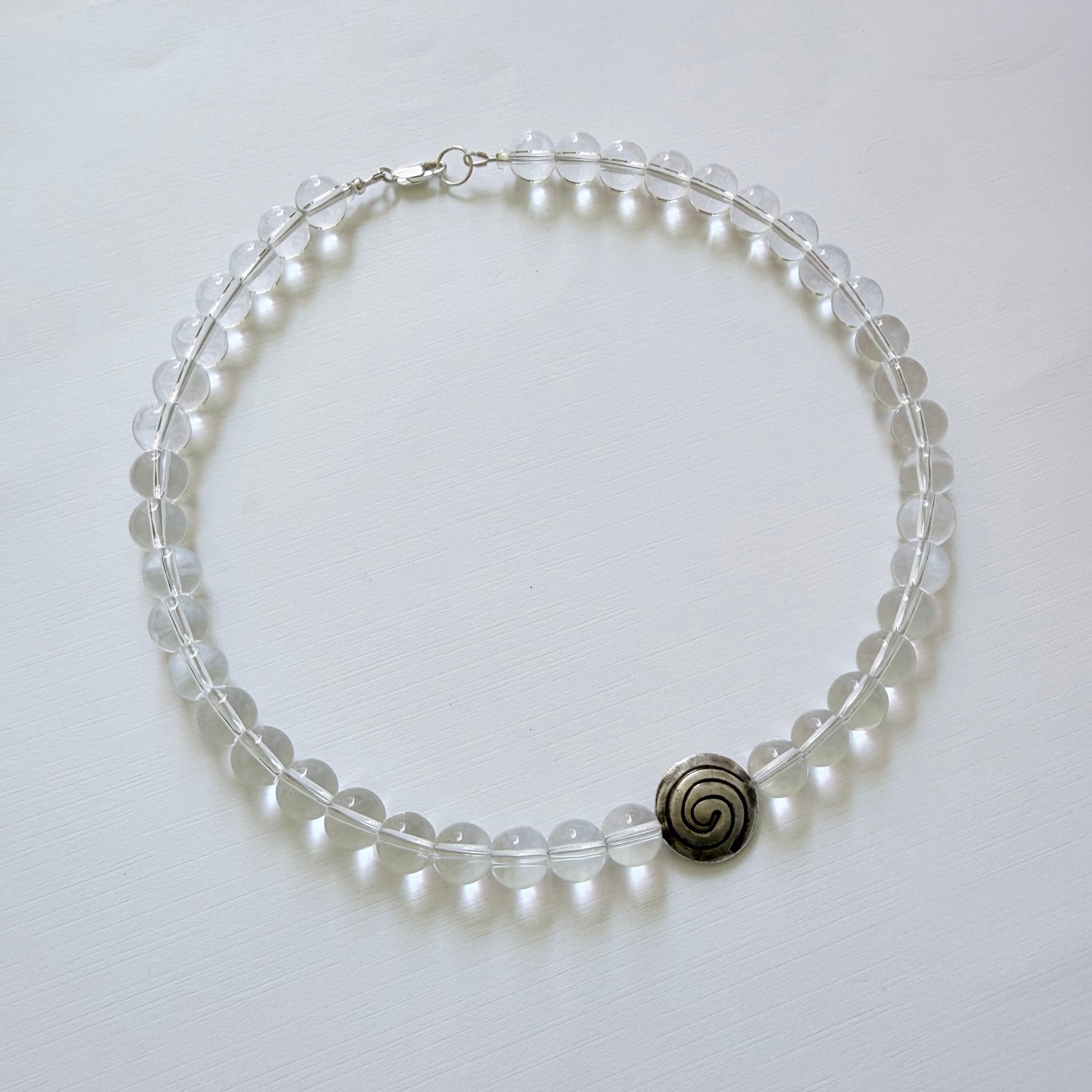 Pearl bracelet with a silver spiral charm on a white background