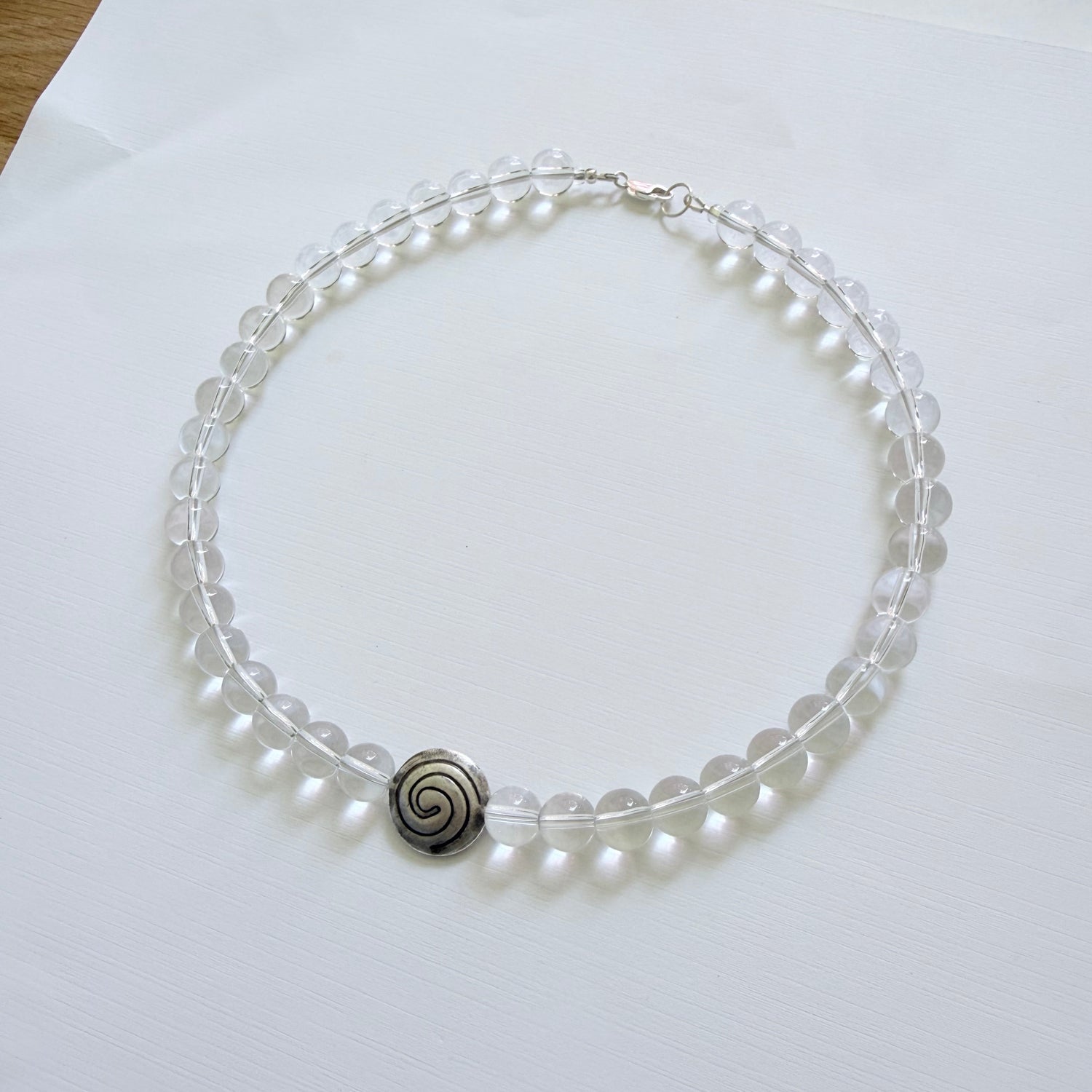 Pearl necklace with a silver clasp on a white surface