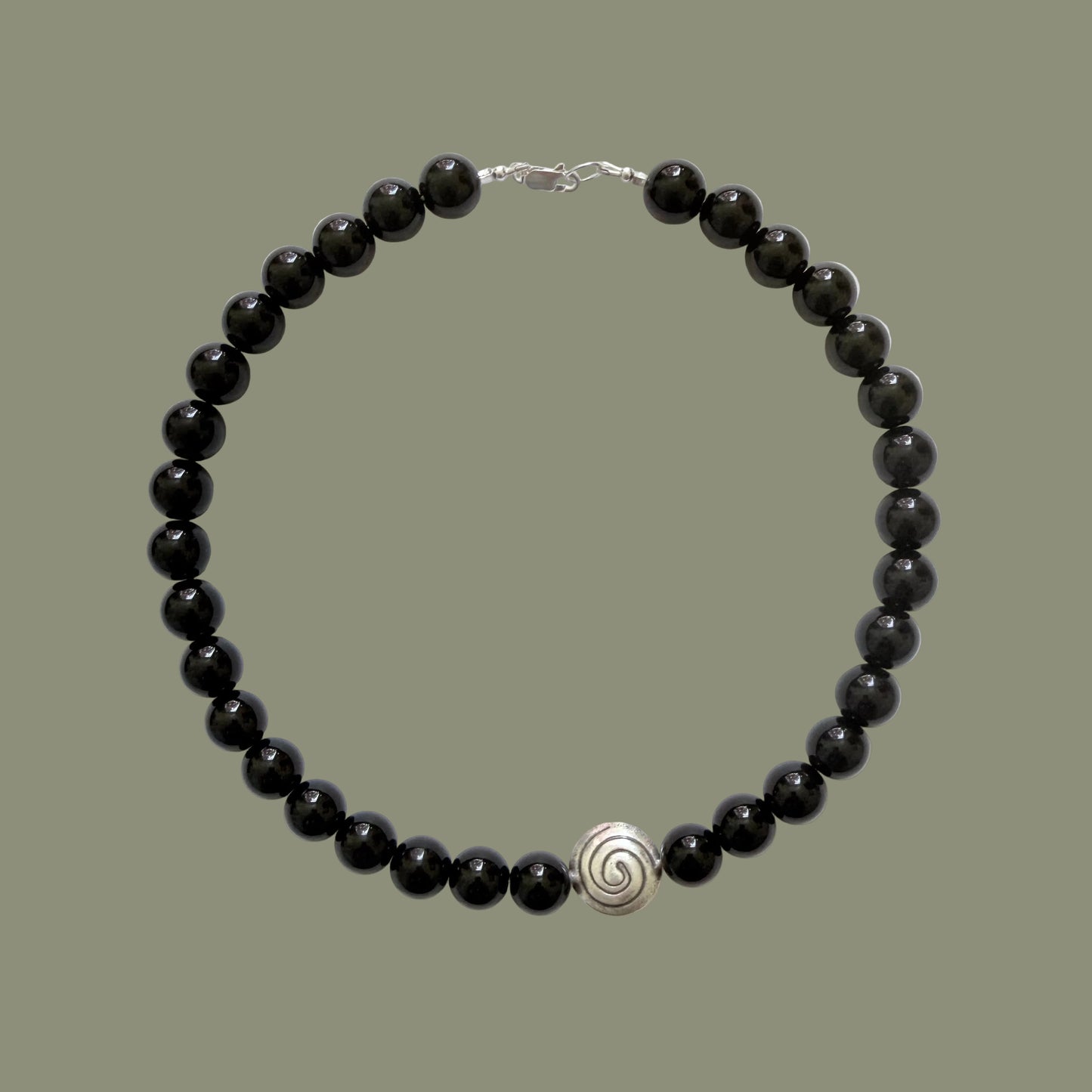 Black beaded necklace with a silver clasp on a white background