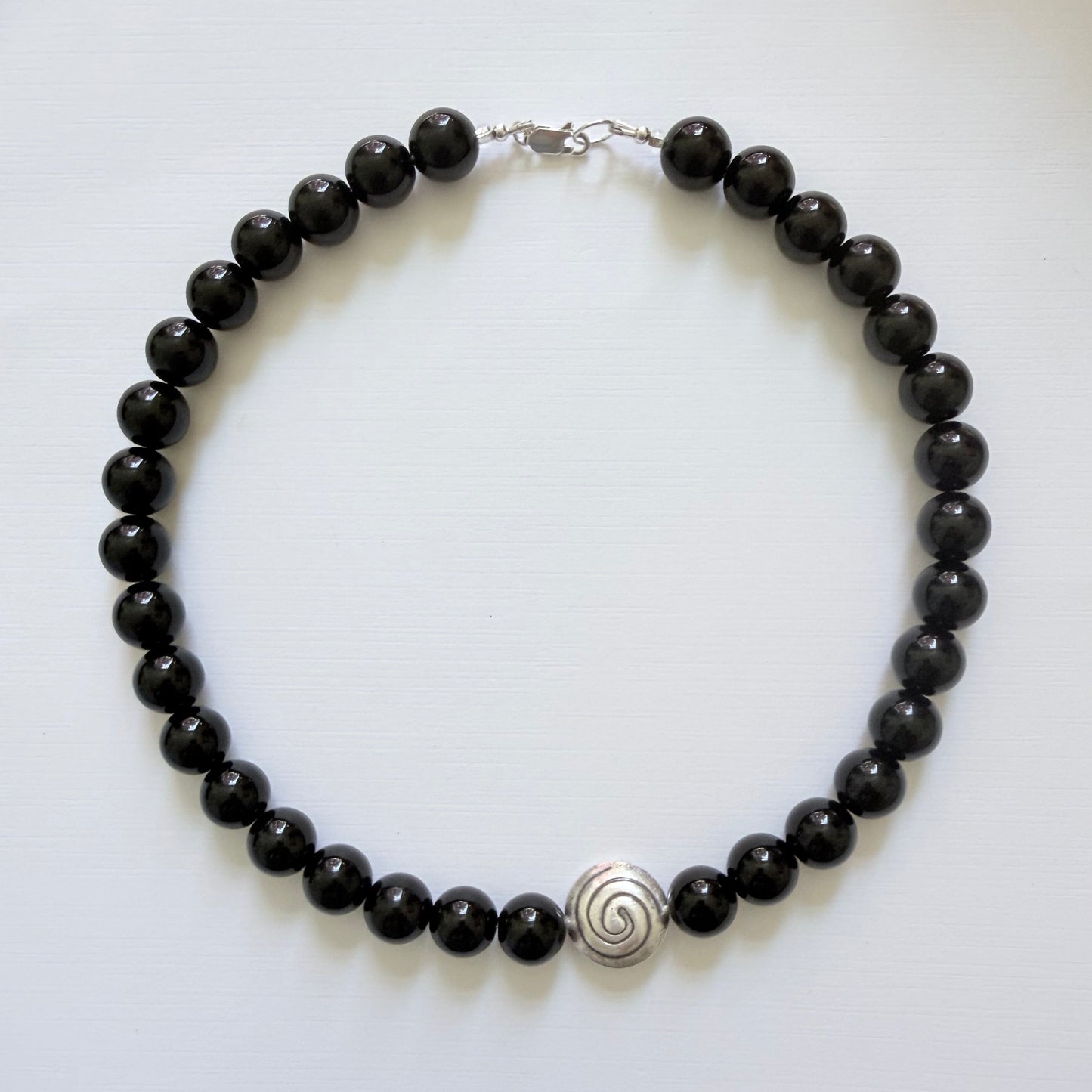 Black beaded bracelet with a silver clasp on a white background