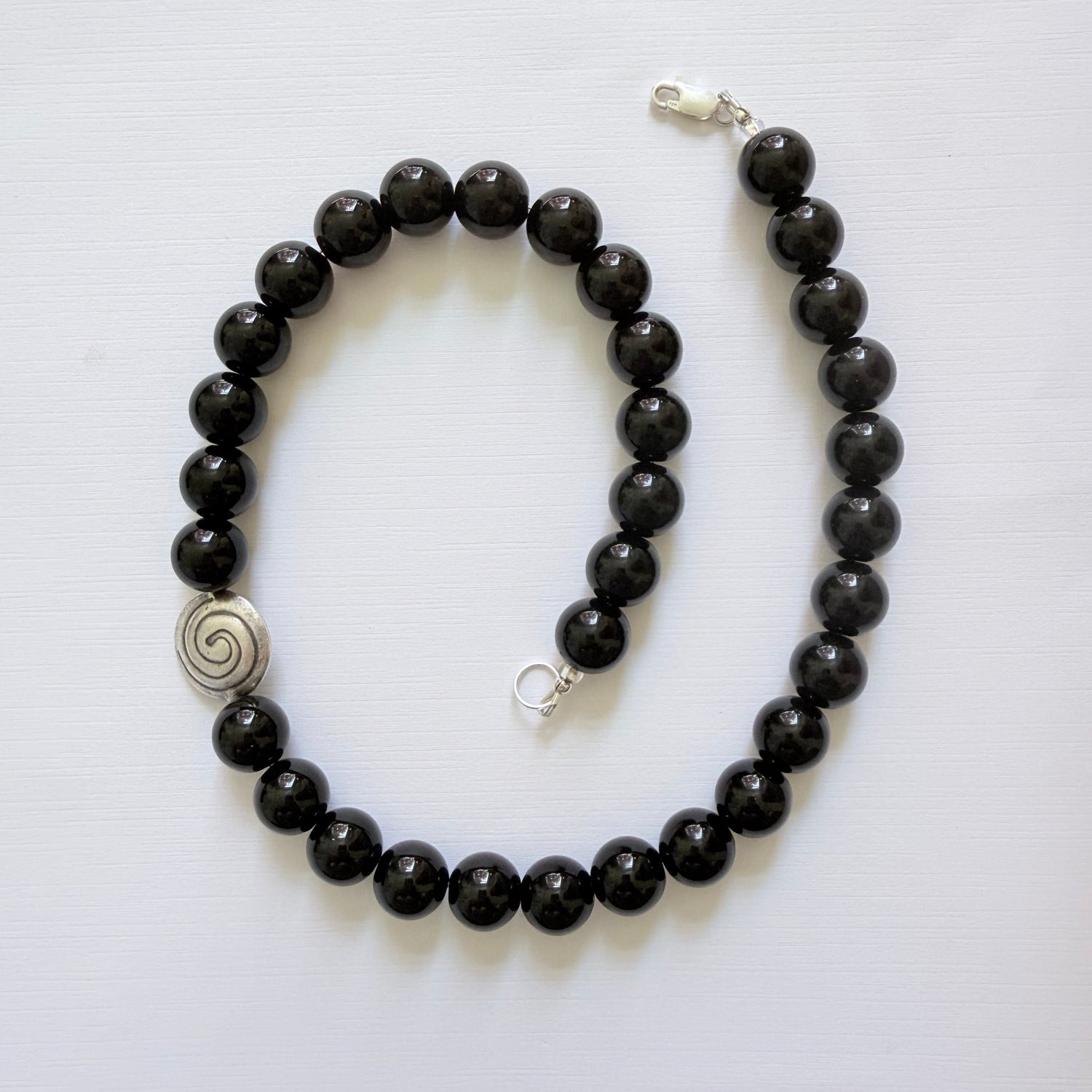 Black beaded bracelet with a silver clasp on a white background