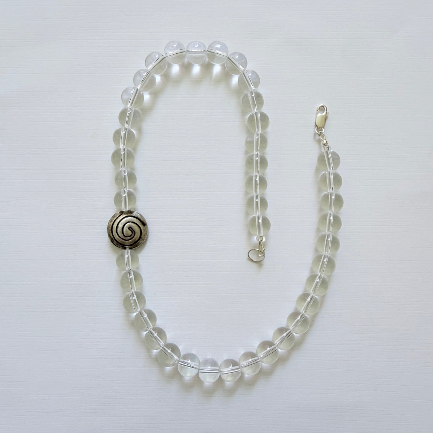 Beaded necklace with a spiral clasp on a light gray background