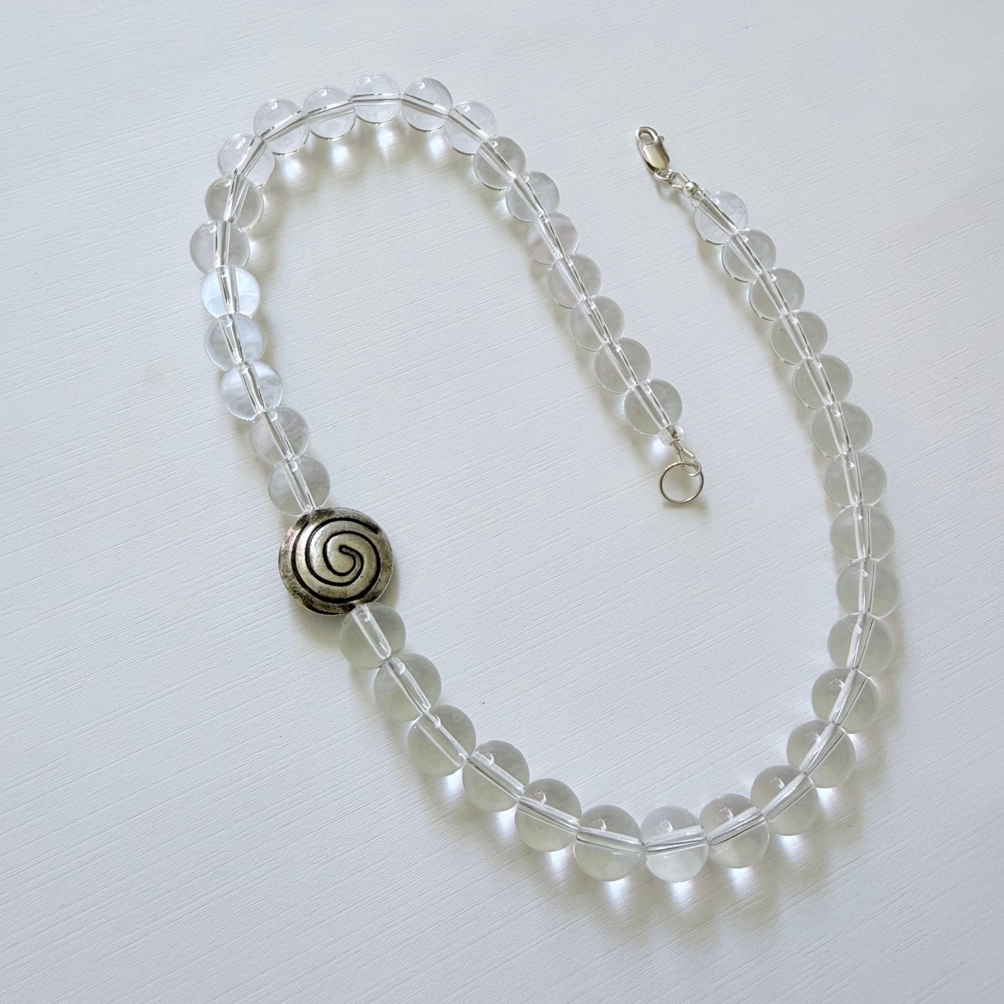 Necklace with clear beads and a silver spiral clasp on a white background