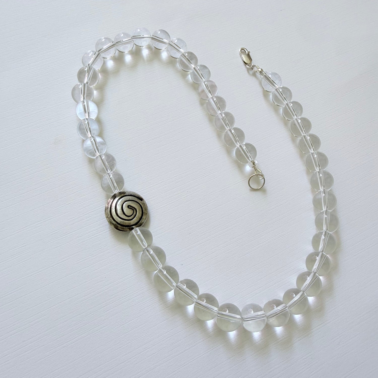 Necklace with clear beads and a silver spiral clasp on a white background