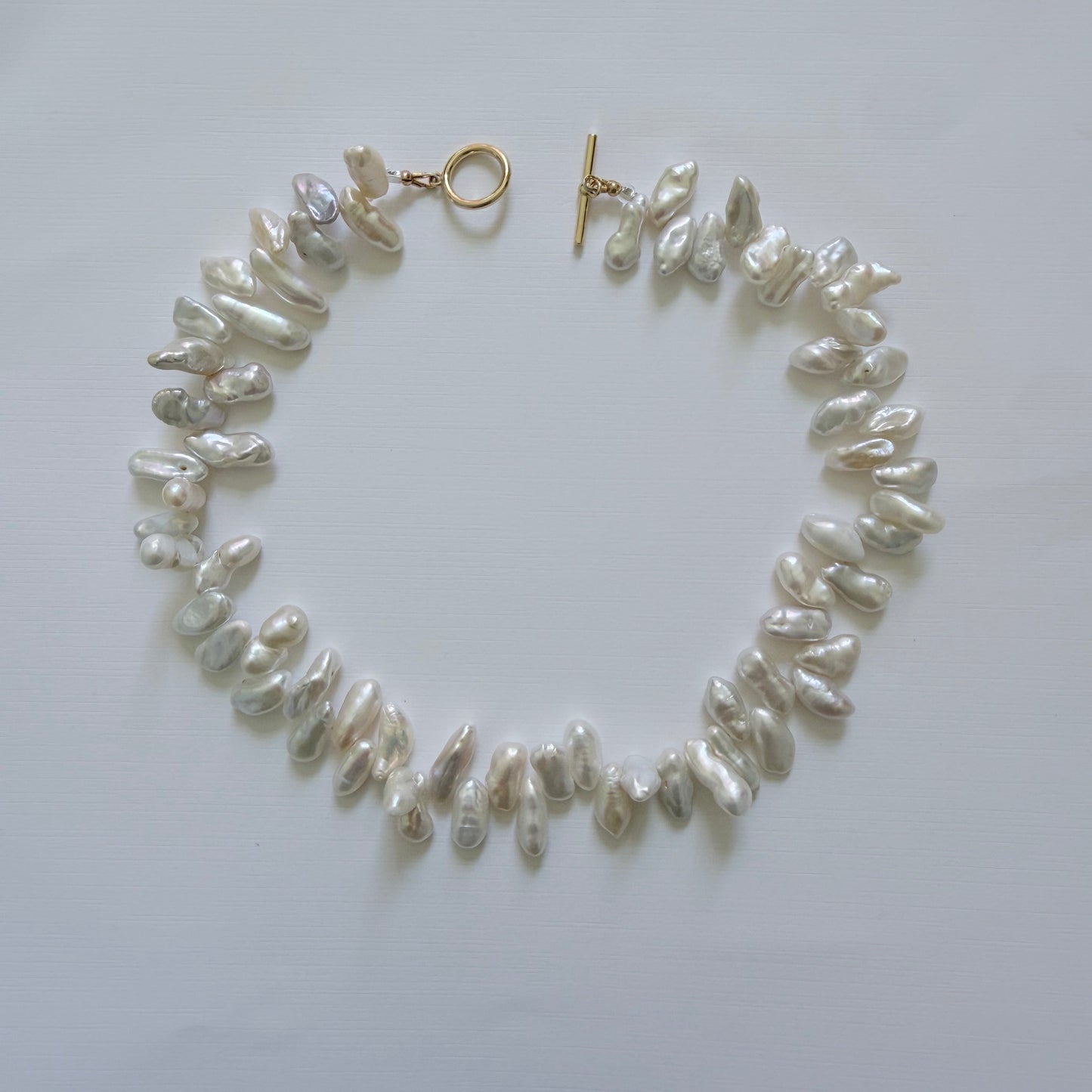 Pearl necklace with gold clasp on a white background