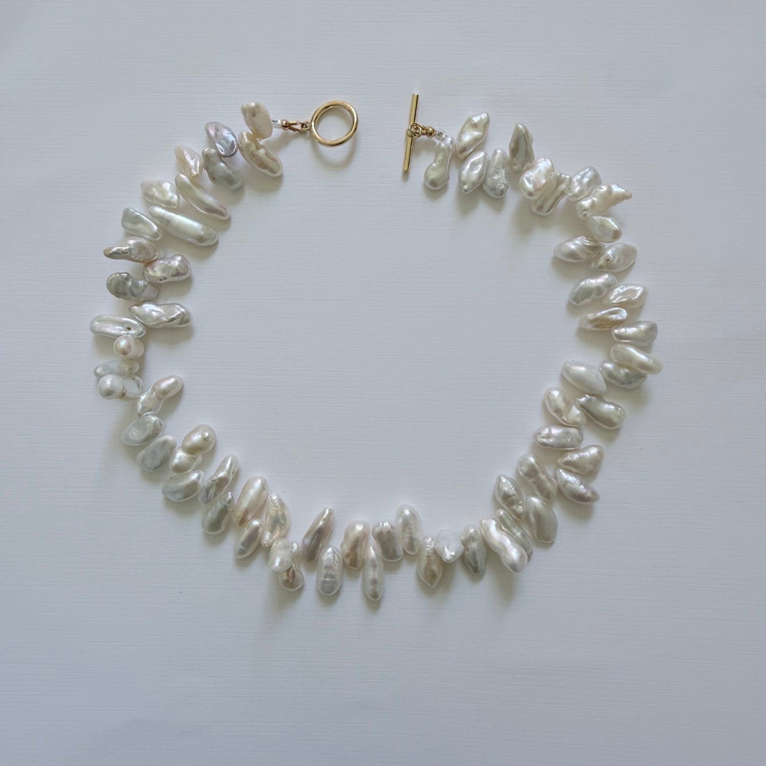 Pearl necklace with gold clasp on a white background