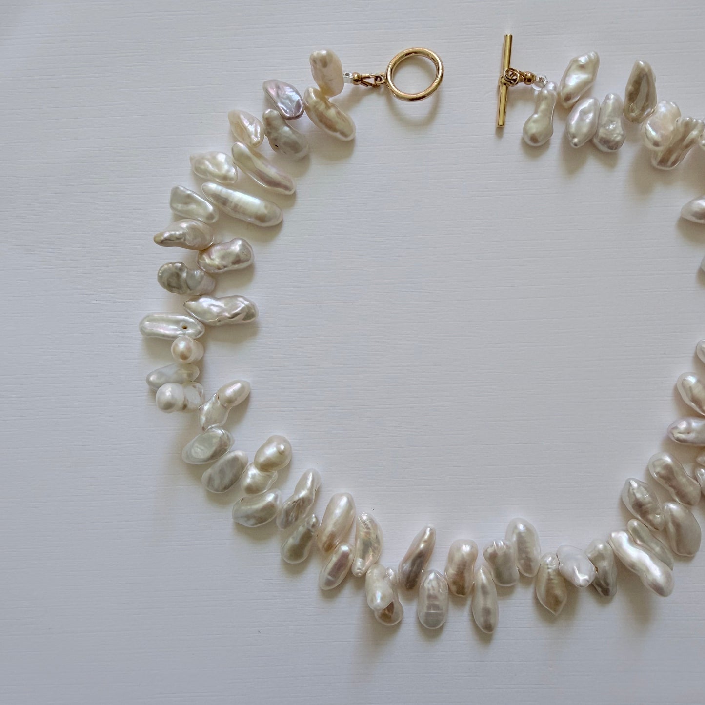 Pearl necklace with a gold clasp on a light gray background