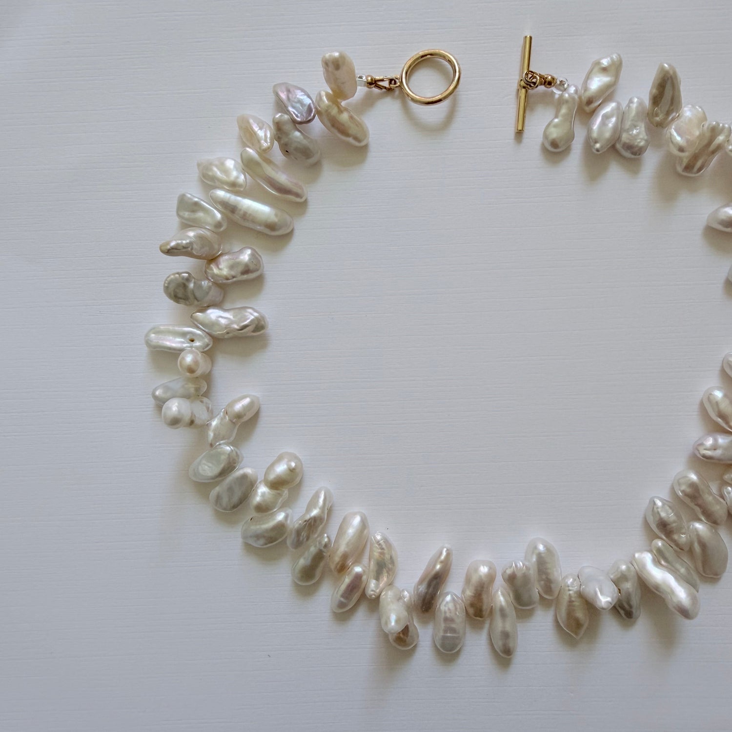 Pearl necklace with a gold clasp on a light gray background