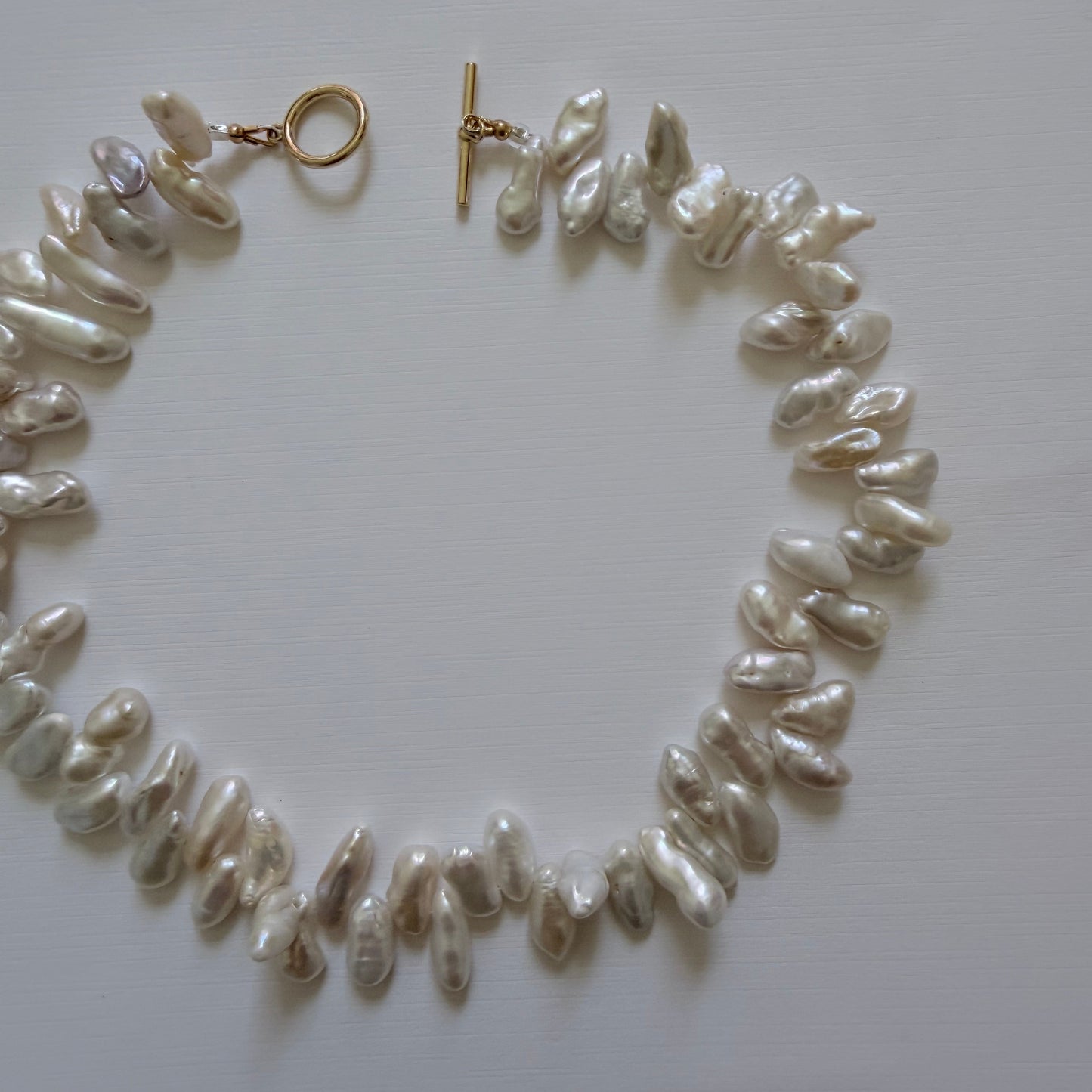 Pearl necklace with gold clasp on a white background