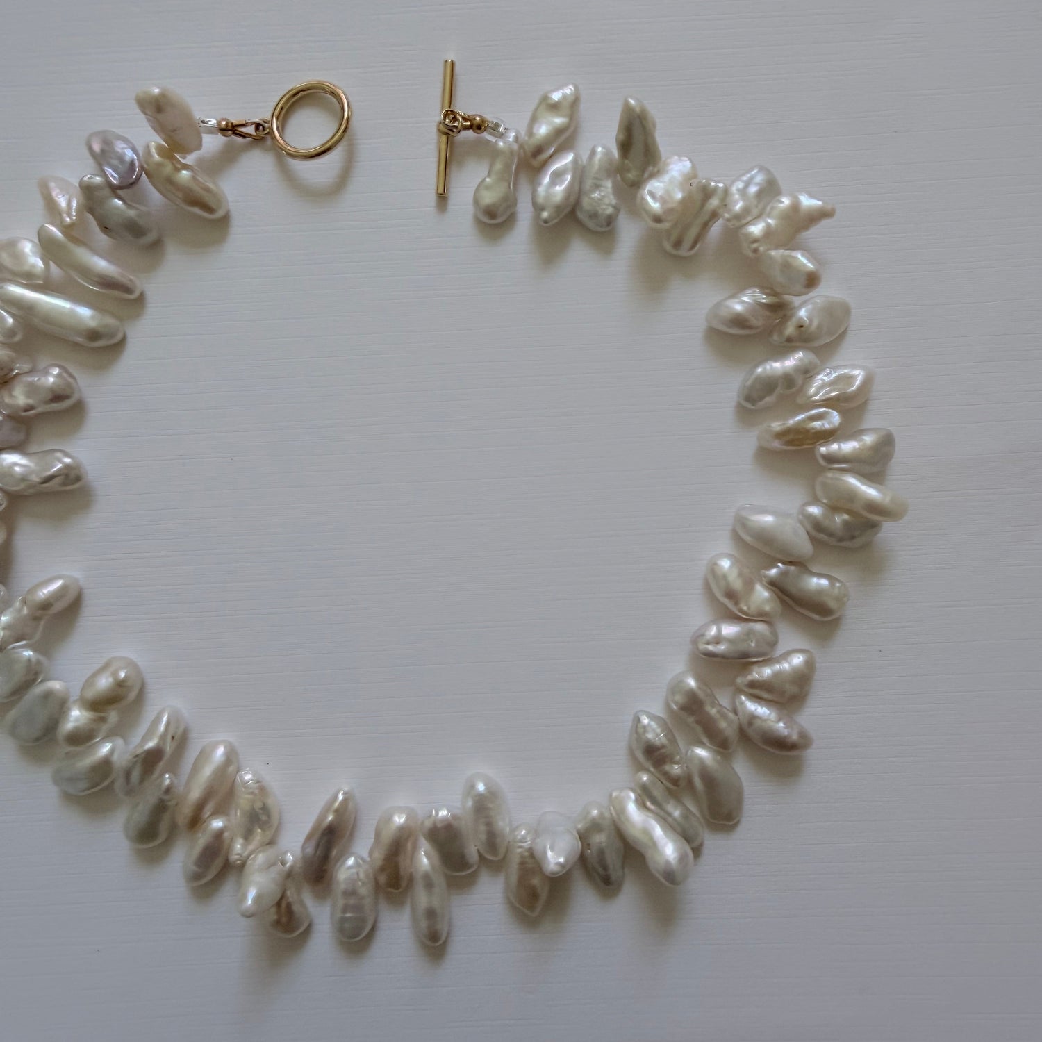 Pearl necklace with gold clasp on a white background