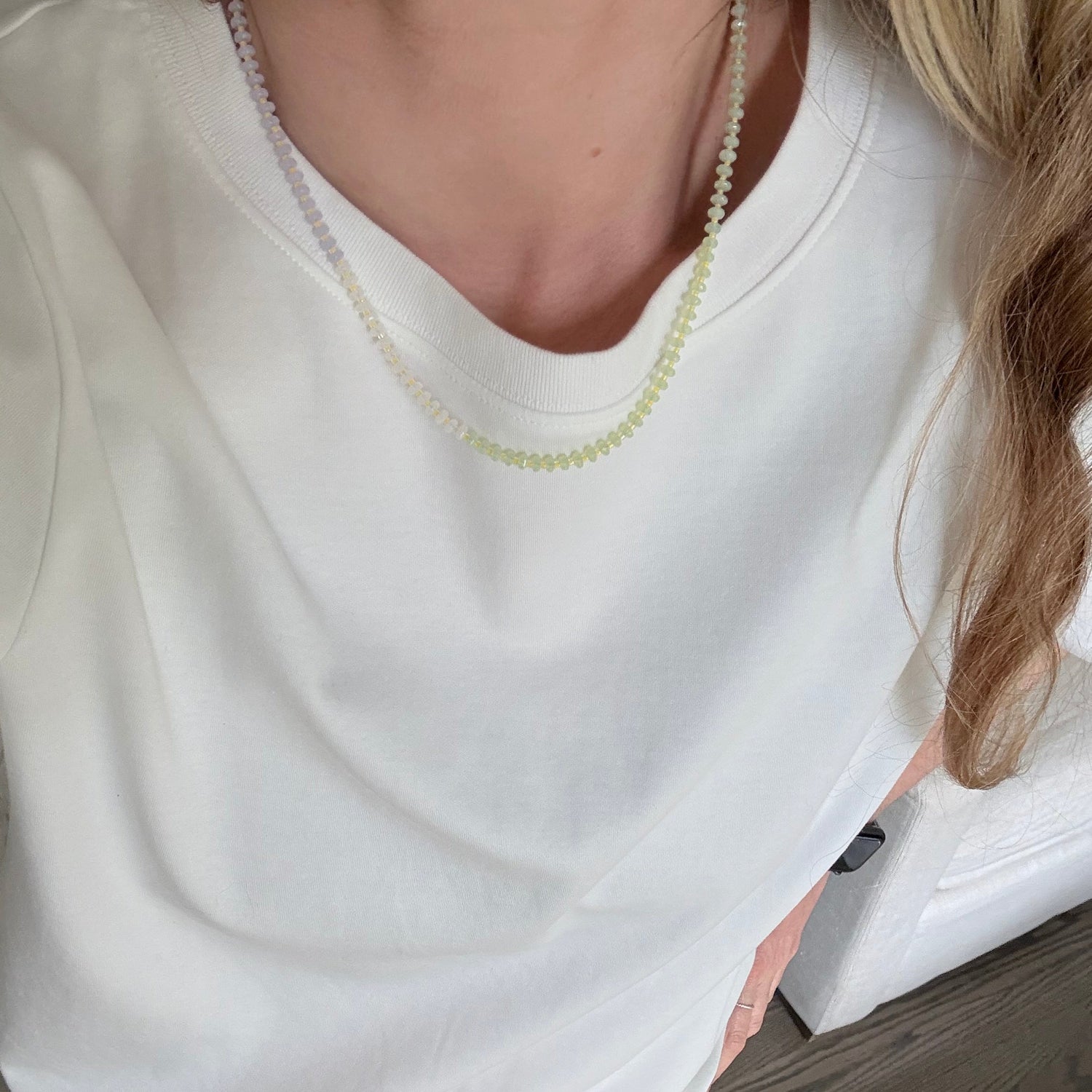 Person wearing a white shirt with a zipper, sitting on a wooden floor.