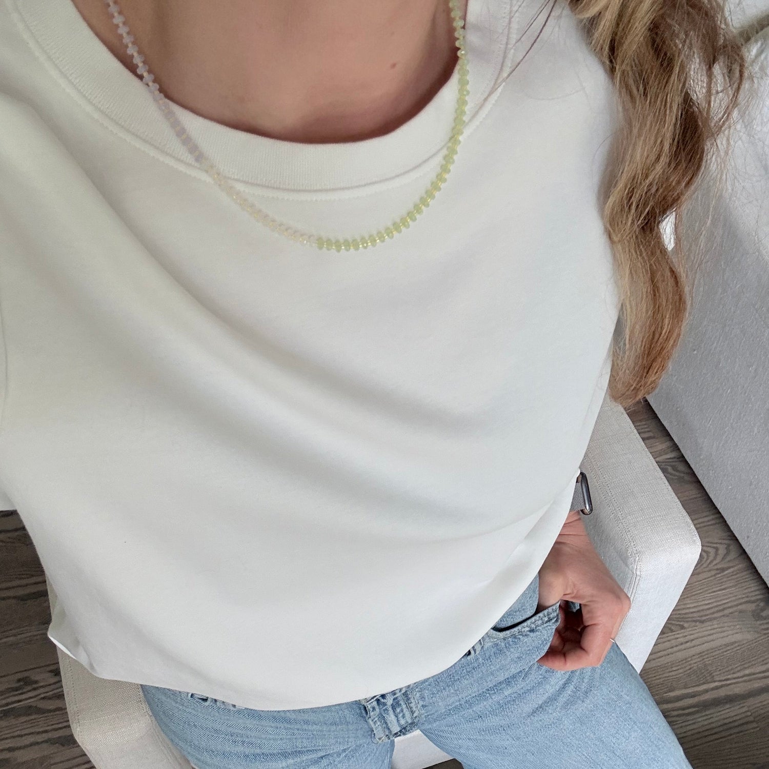 Person sitting on a chair wearing a white top and light blue jeans.
